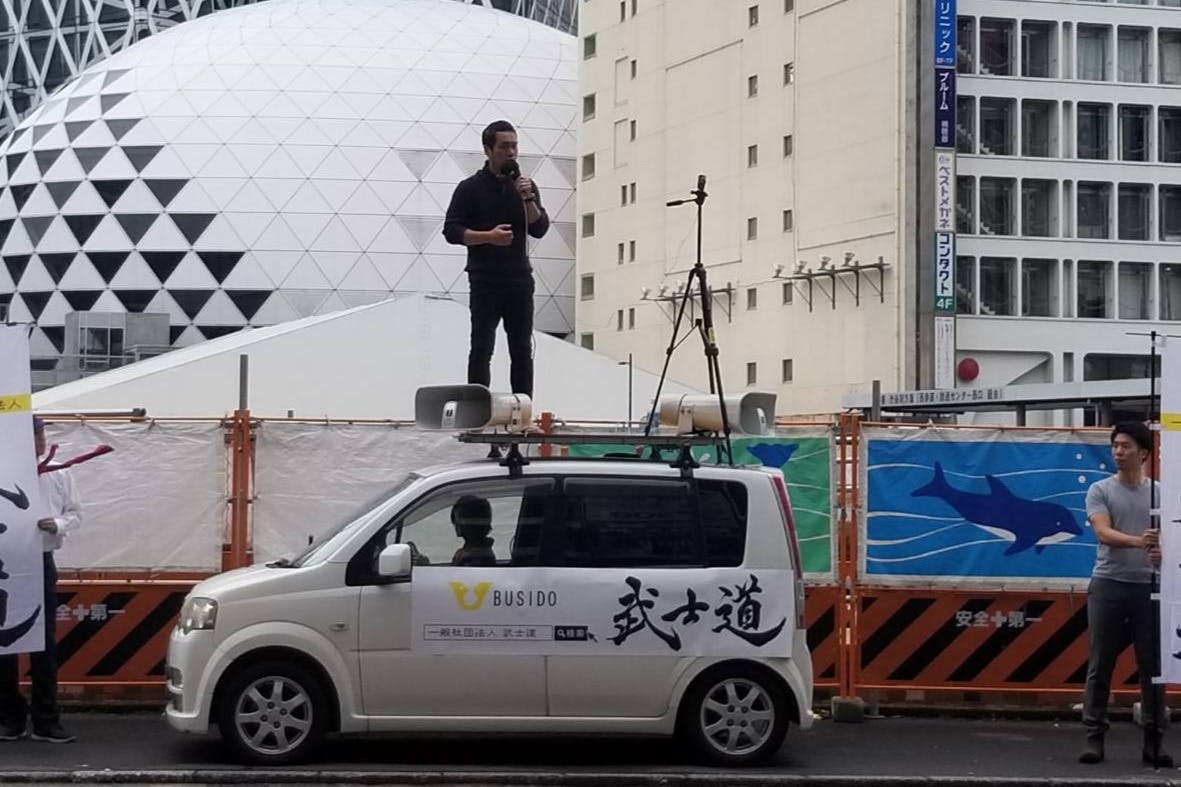 街宣カーに乗り、街頭演説する与国