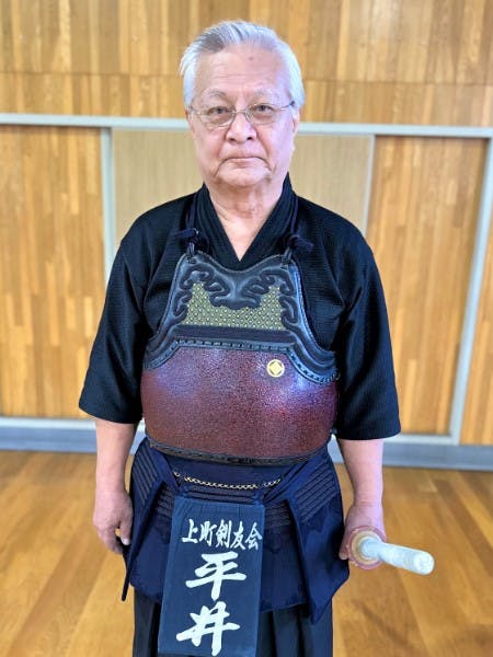 竹刀を持ち微笑む剣道着の男性